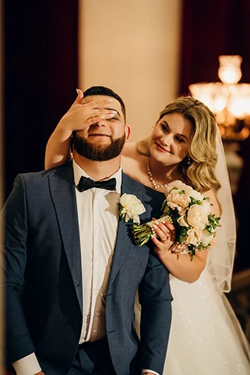 Невеста прикрывает ладонью глаза жениха