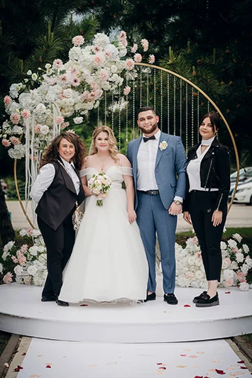 Жених и невеста на цветочной арке с гостями свадьбы